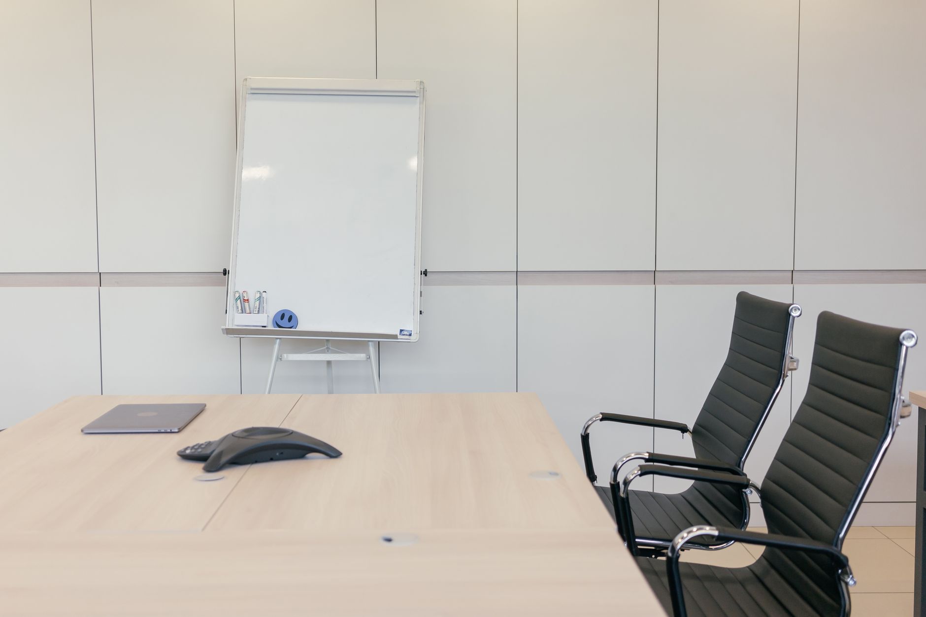 An empty modern meeting room with a table, chairs and a whiteboard