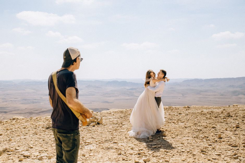 Wedding photographer capturing a couple embracing on a desert clifftop