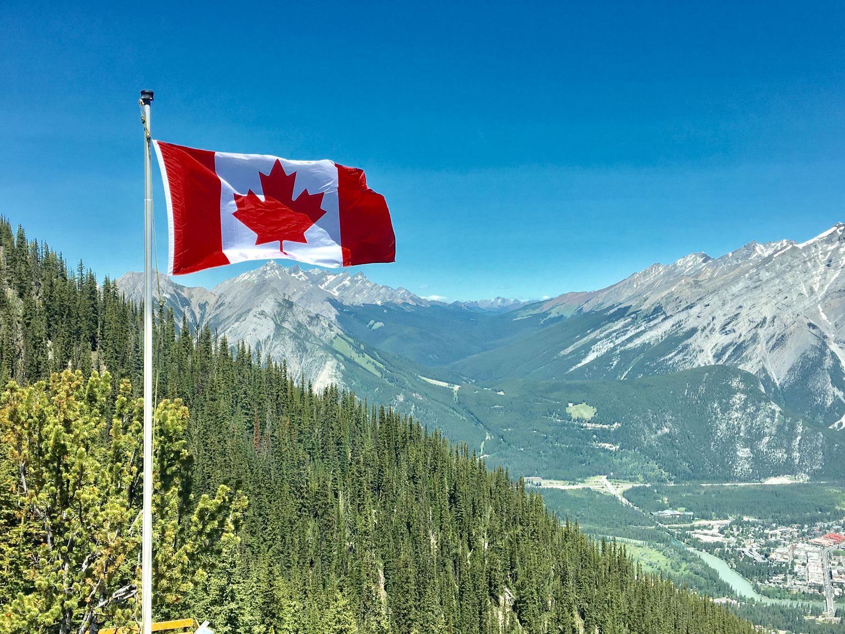 Canadian flag flying above a mountain landscape